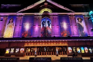 Un théâtre orné de grandes banderoles publicitaires pour le film « La Belle et la Bête », d’un auvent et d’une série d’affiches de films illuminées.