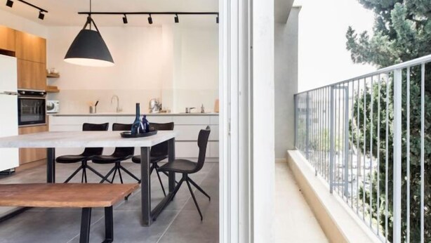 Eine moderne Küche mit Essbereich, einem großen Fenster und einem Balkon mit Geländer.