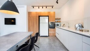 Eine moderne Küche mit Essbereich, einem an der Wand montierten Fernseher und einer großen Pendelleuchte.