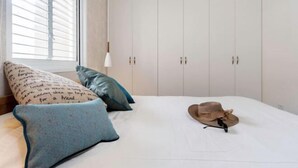 Ein Schlafzimmer mit einem Bett, Kissen, einem Hut und einem Kleiderschrank.