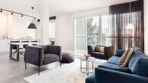 Ein modernes Wohnzimmer mit einer Couch, Sesseln, einem Couchtisch und einem Essbereich mit Tisch und Stühlen.