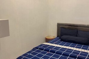 A bedroom with a bed, a headboard, and a small round table with a lamp. - Yuriti Modern Minimalis Villa (Batu Sub-District)
