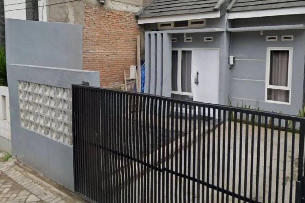 A gated residential area with a grey house, a brick wall, and a metal fence.