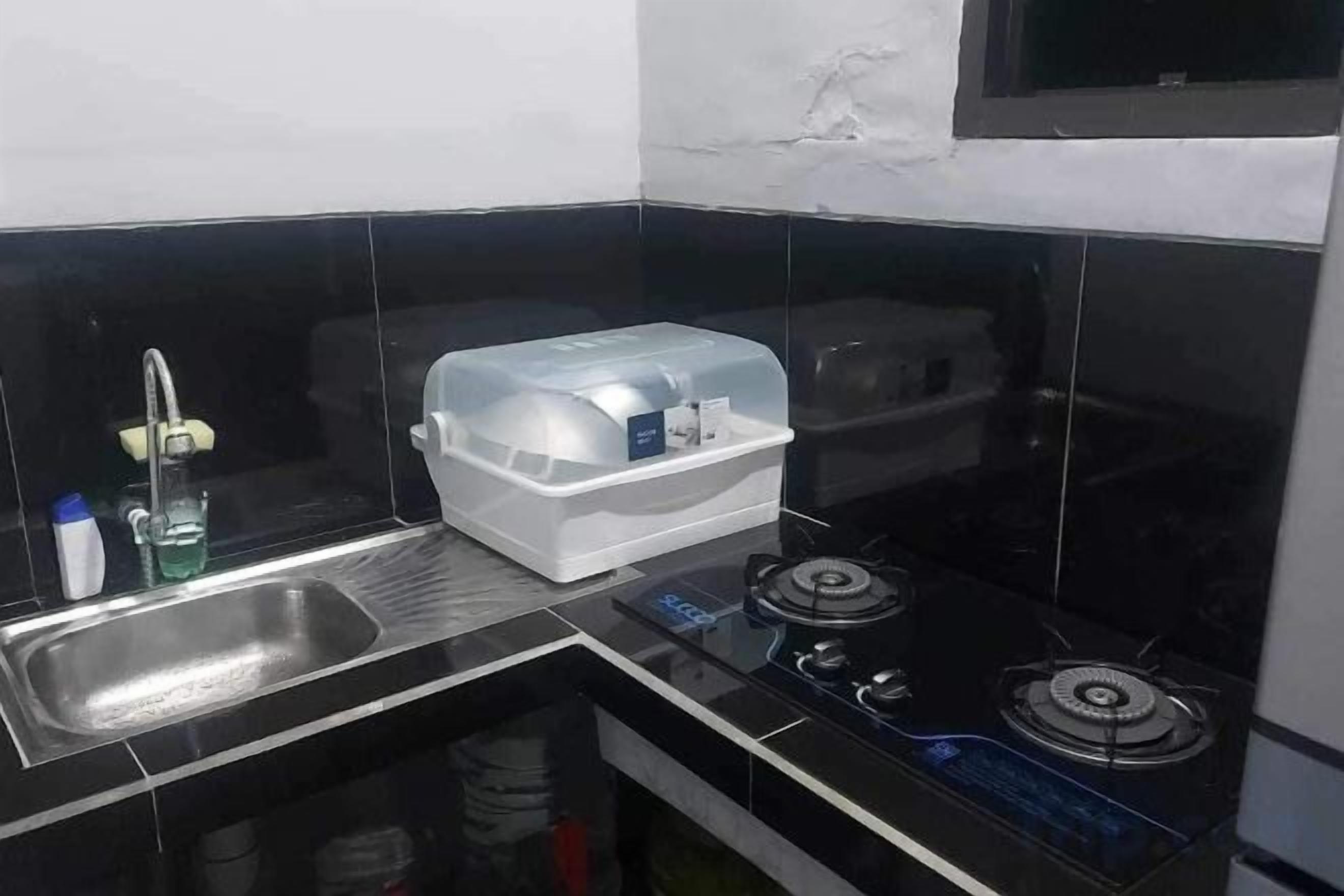 A kitchen with a sink, a stove, and a storage container.