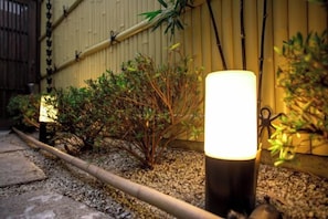 A garden with a pathway, a lamp post, and a bamboo fence. - Shukuhonjin Gamo (Osaka)
