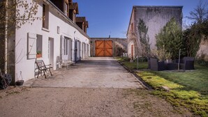 Un patio con un edificio que tiene una puerta de madera grande, un banco y una planta en maceta.
