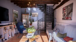 Ein Wohnzimmer mit einer Couch, einem Couchtisch, einem Bücherregal, einem Sessel und einer Treppe.