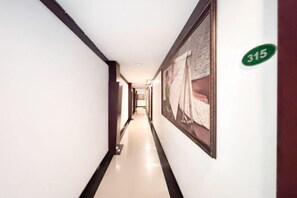 A hotel corridor with a framed picture on the wall, a number sign, and a clean floor. - RedDoorz @ First Homestay Bypass Kuta (Bali)
