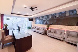 A modern living room with a sofa set, a coffee table, and a TV mounted on the wall. - RedDoorz @ First Homestay Bypass Kuta (Bali)