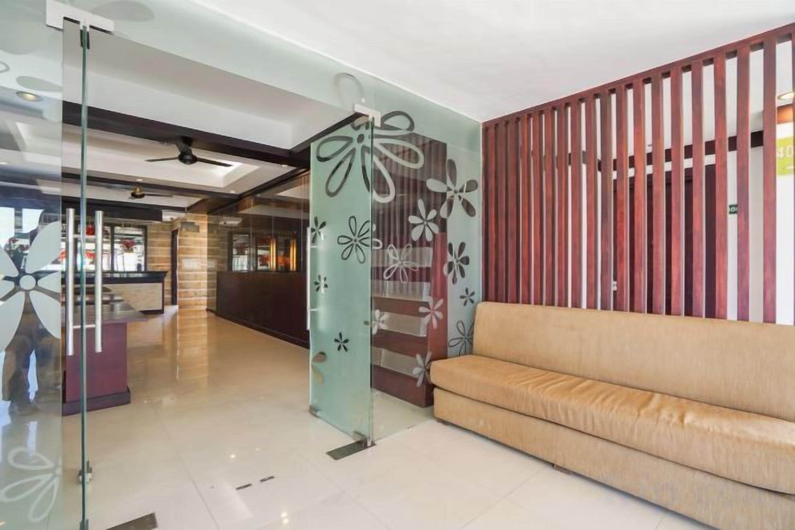 A reception area with a glass partition, a sofa, and a wooden partition.
