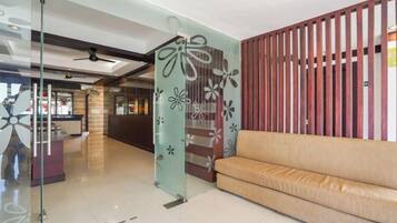 A reception area with a glass partition, a sofa, and a wooden partition.