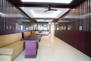 A modern interior with seating areas, a ceiling fan, and a view through a glass wall. - RedDoorz @ First Homestay Bypass Kuta (Bali)