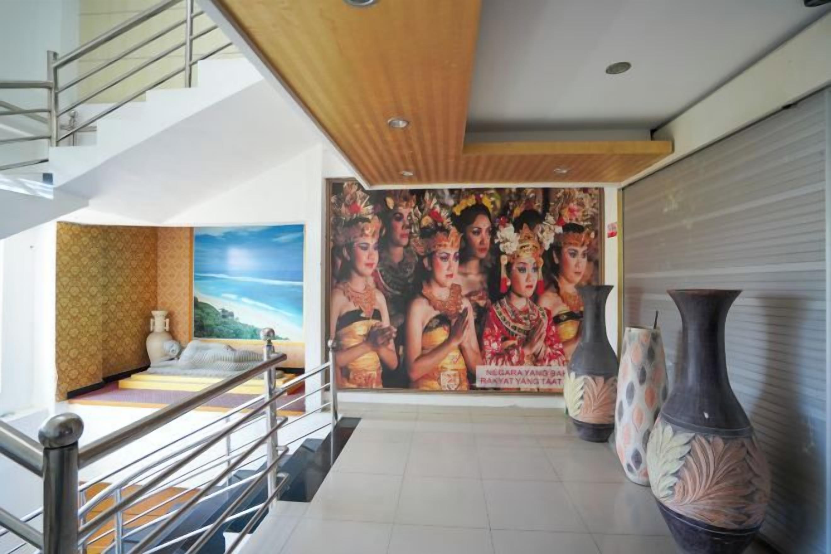 A hotel lobby with a staircase, a large mural, and decorative vases.