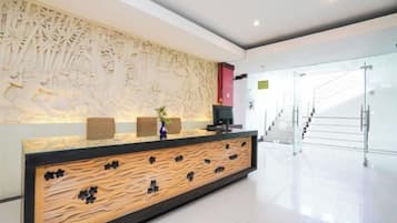 A reception area with a modern design, featuring a reception desk, a decorative wall, and a staircase in the background.