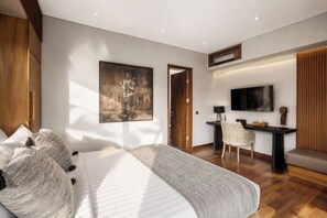 Een moderne slaapkamer met een bed, een bureau, een stoel en een televisie.