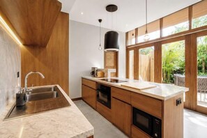 Een moderne keuken met een marmeren aanrechtblad, houten kastjes en een groot raam met uitzicht op de omgeving.