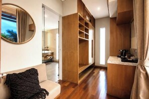 A modern interior with a wooden floor, a sofa, a large mirror, and a built-in wooden shelving unit. - Villa Na (Bali)