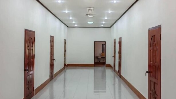 A hallway with white walls, wooden doors, and a tiled floor.