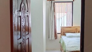 A room with a wooden bed, a curtain, and a window.