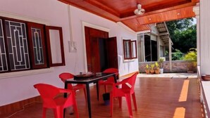 A dining area with a wooden ceiling, a table with red chairs, and a view of the outdoors.