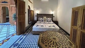 A room with a bed, a wooden cabinet, a patterned floor, and an open doorway leading to a balcony. - Welcoming to room in Riad bed & breakfast with AC in charming Fez authentic (Fès)