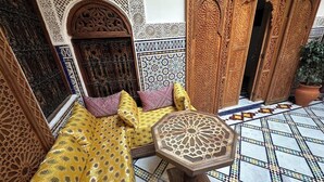 A traditional Moroccan interior with a patterned sofa, intricate wooden doors, and a tiled floor. - Welcoming to room in Riad bed & breakfast with AC in charming Fez authentic (Fès)