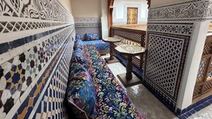 A corridor with a patterned floor, a sofa with a floral upholstery, and a small table with a decorative base. - Welcoming to room in Riad bed & breakfast with AC in charming Fez authentic (Fès)