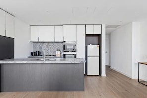 Una cocina moderna con una isla de mármol, electrodomésticos de acero inoxidable y armarios blancos.