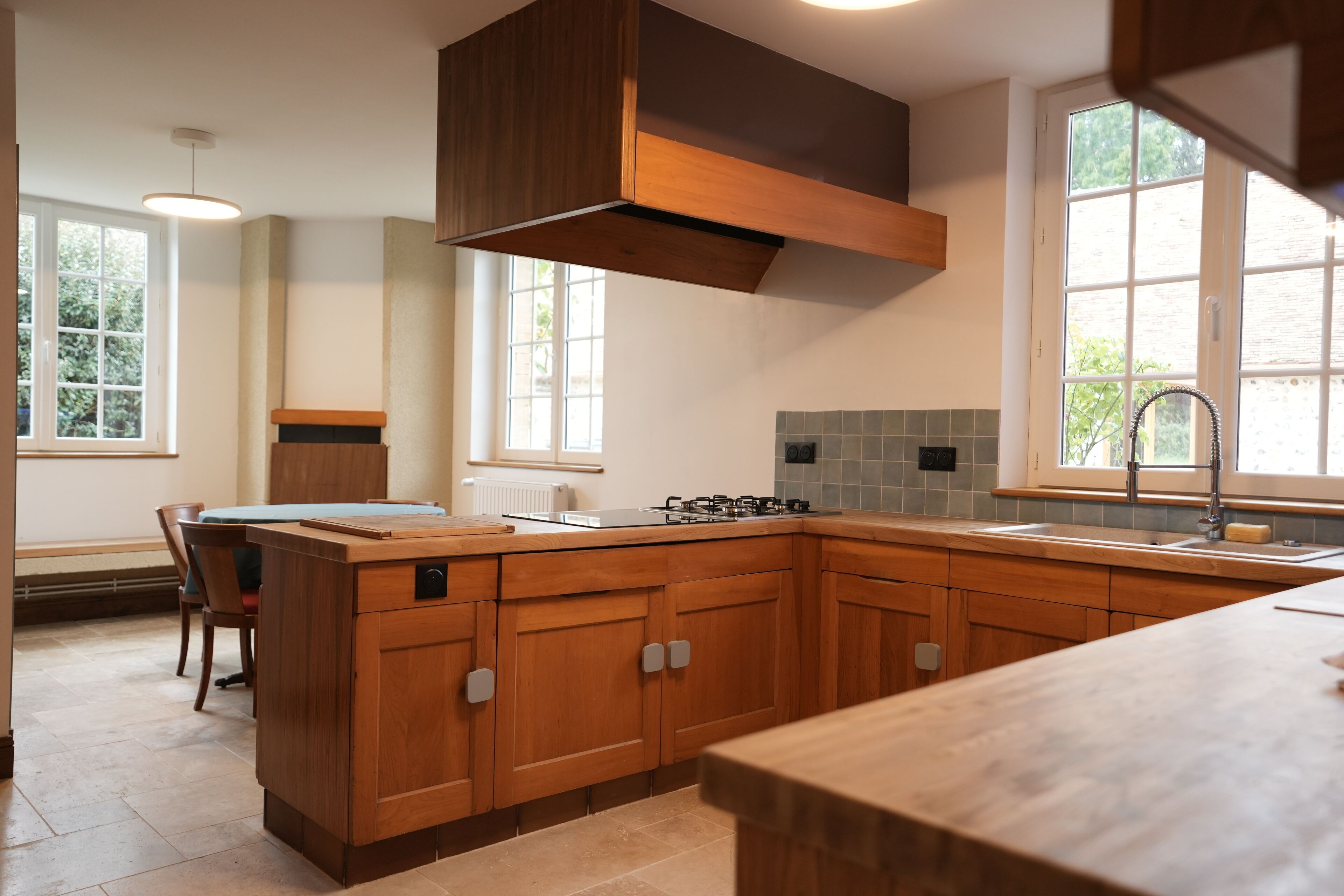 Une cuisine moderne avec des meubles en bois, un îlot central et une grande fenêtre qui laisse entrer la lumière naturelle.