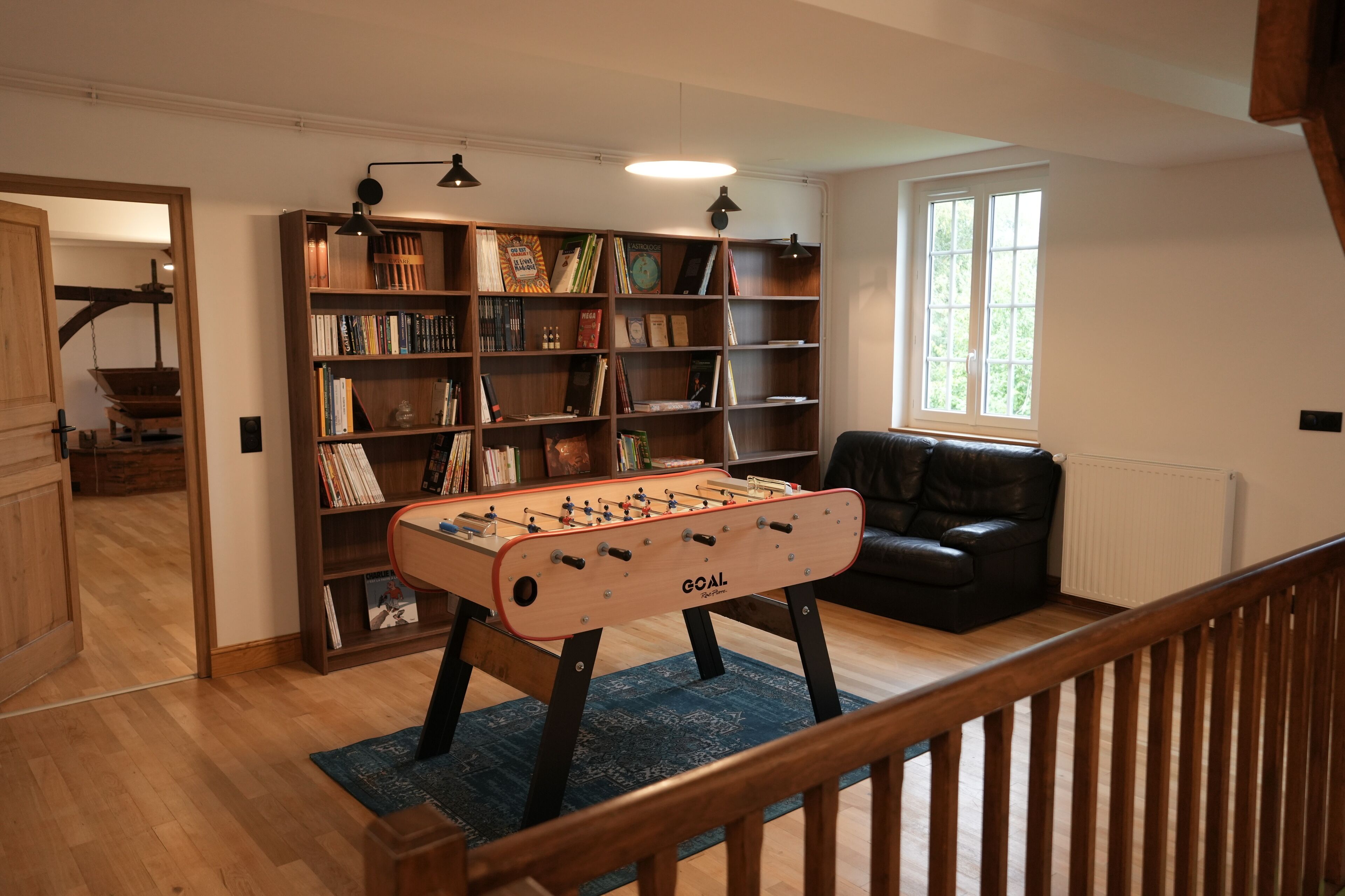 Une pièce chaleureuse avec un baby-foot, une bibliothèque et un canapé en cuir.