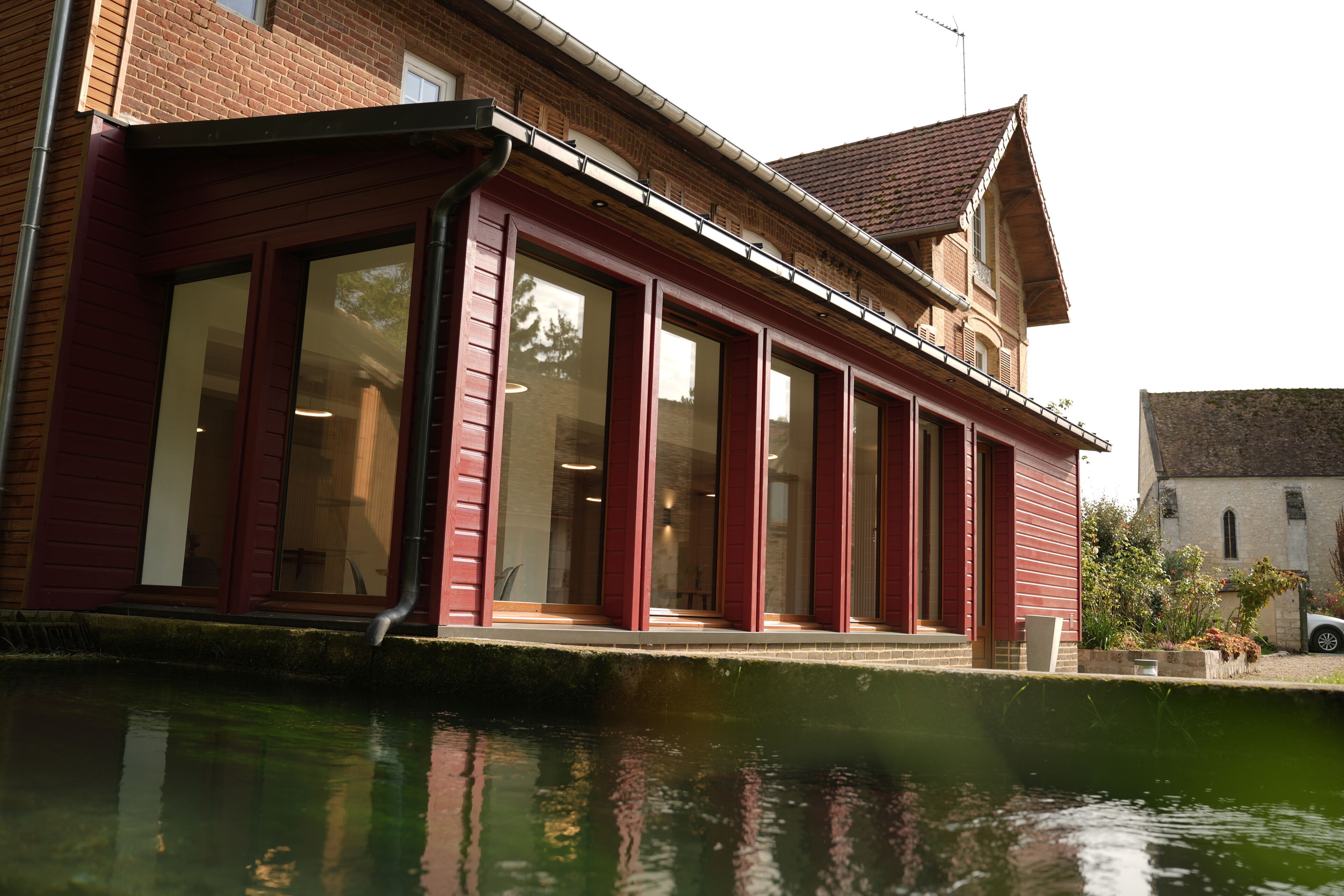 A red-brick building with large windows and a water feature in front.