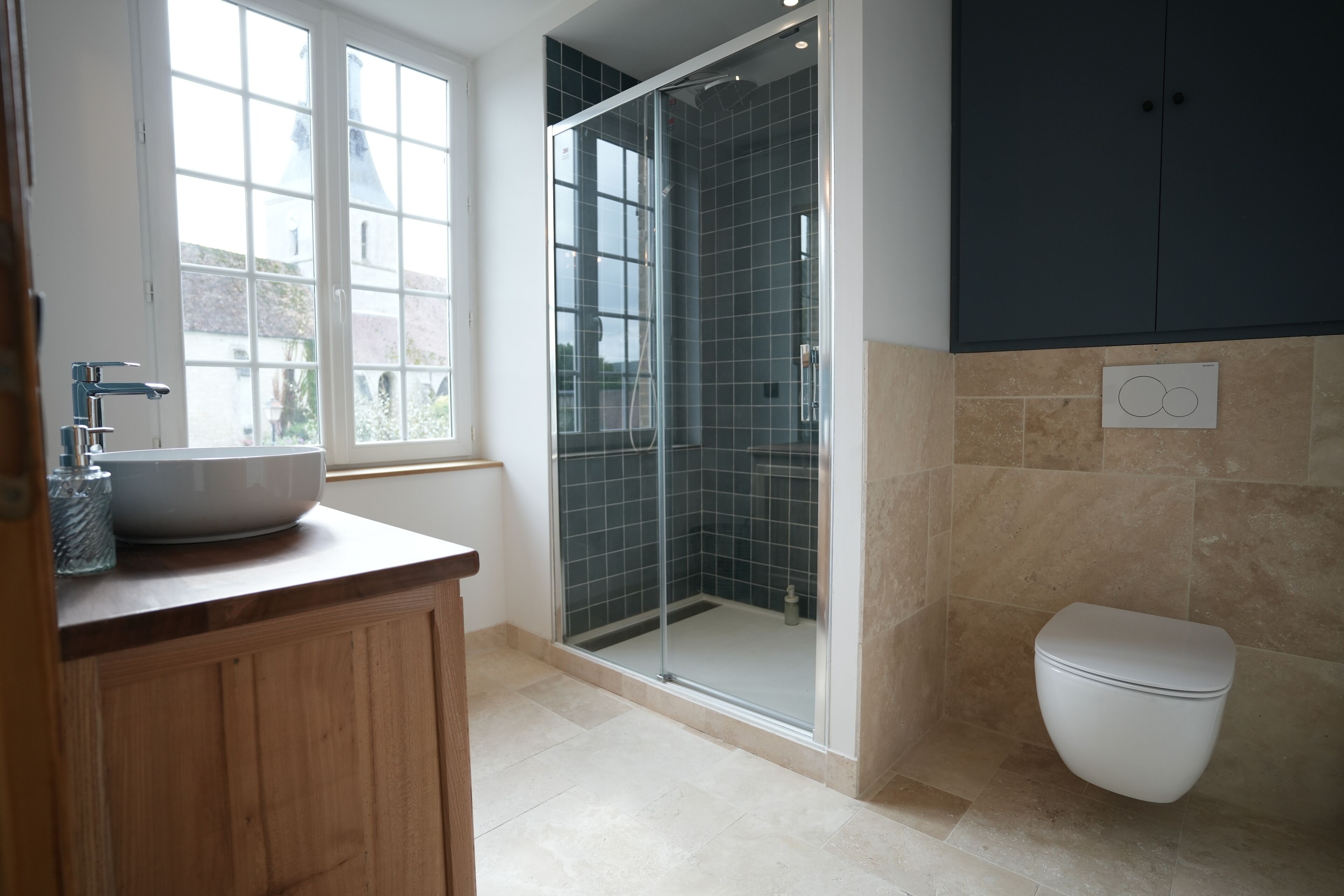 Un bagno moderno con doccia vetrata, un water bianco e un ampio lavabo su un piano d'appoggio in legno.