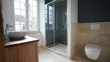 Un bagno moderno con doccia vetrata, un water bianco e un ampio lavabo su un piano d'appoggio in legno.