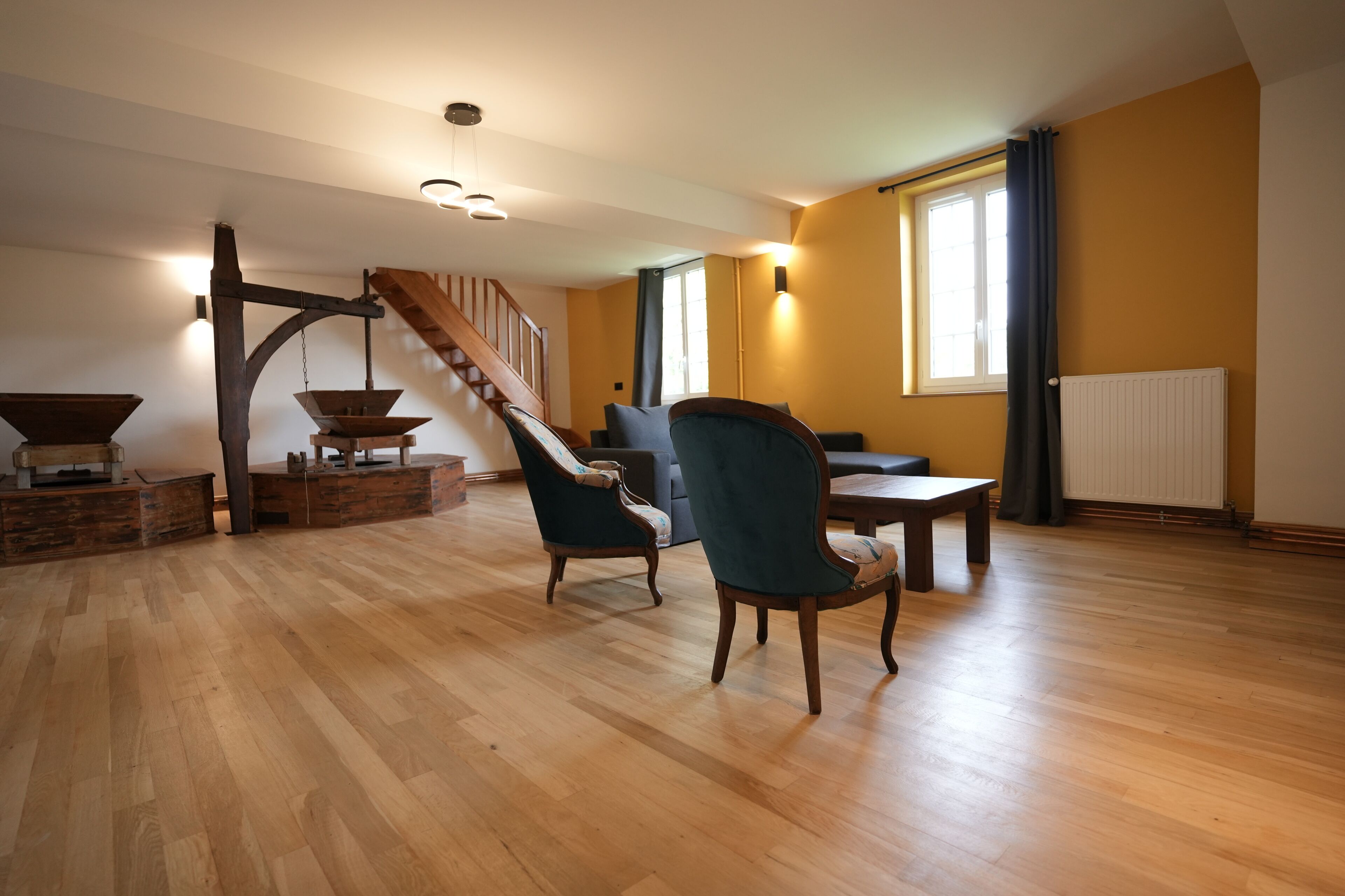 Ein geräumiges Zimmer mit Holzboden, einer Treppe, einem Esstisch und zwei Stühlen.