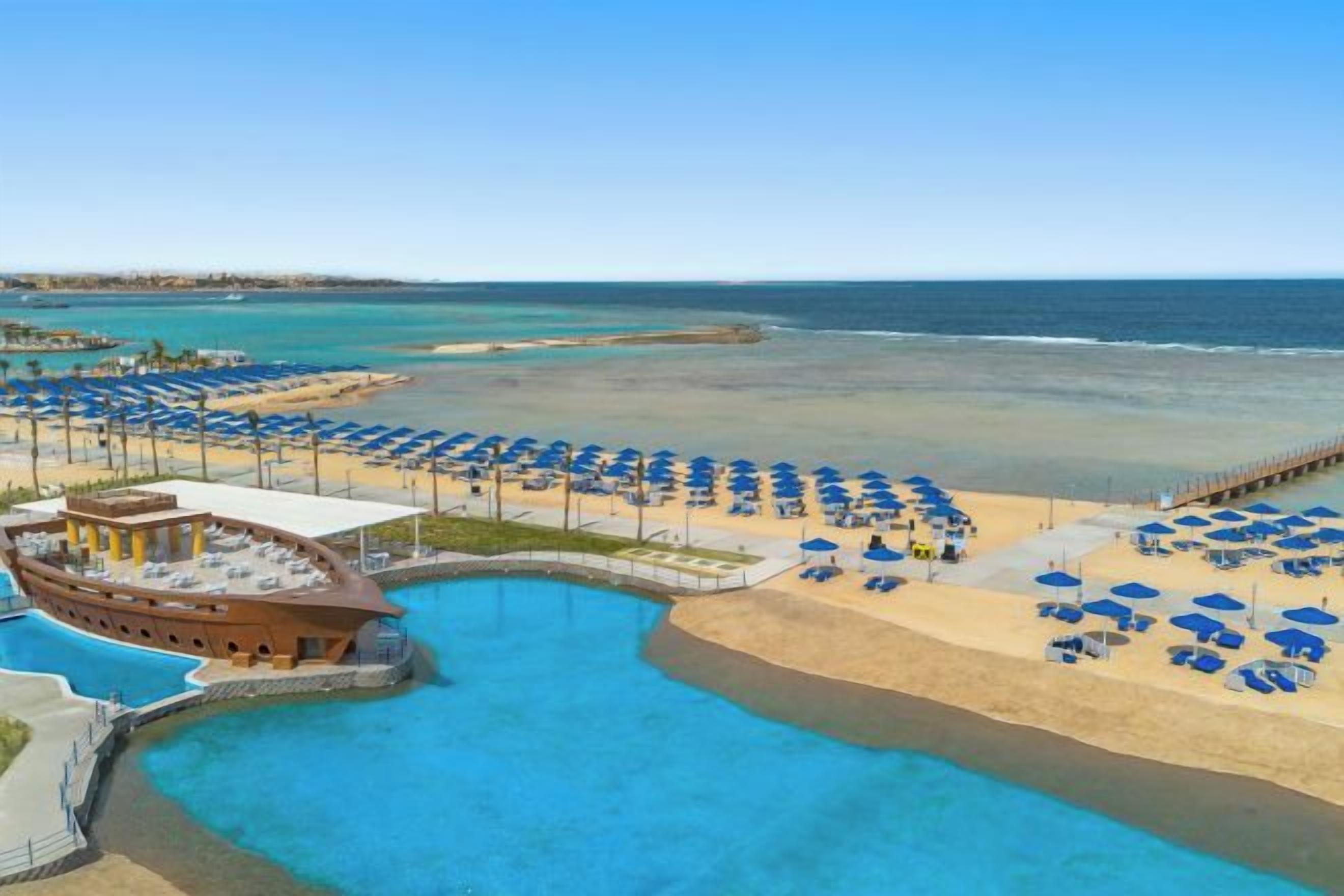 Un complexe hôtelier doté d’une piscine, d’une plage et de nombreux parasols.