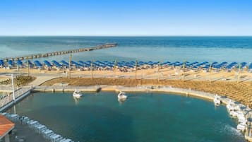 A coastal area with a marina, beach umbrellas, and lounge chairs.