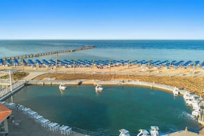 A coastal area with a marina, beach umbrellas, and lounge chairs. - Albatros Makadi Resort - 24 HRS All Inclusive (Hurghada)