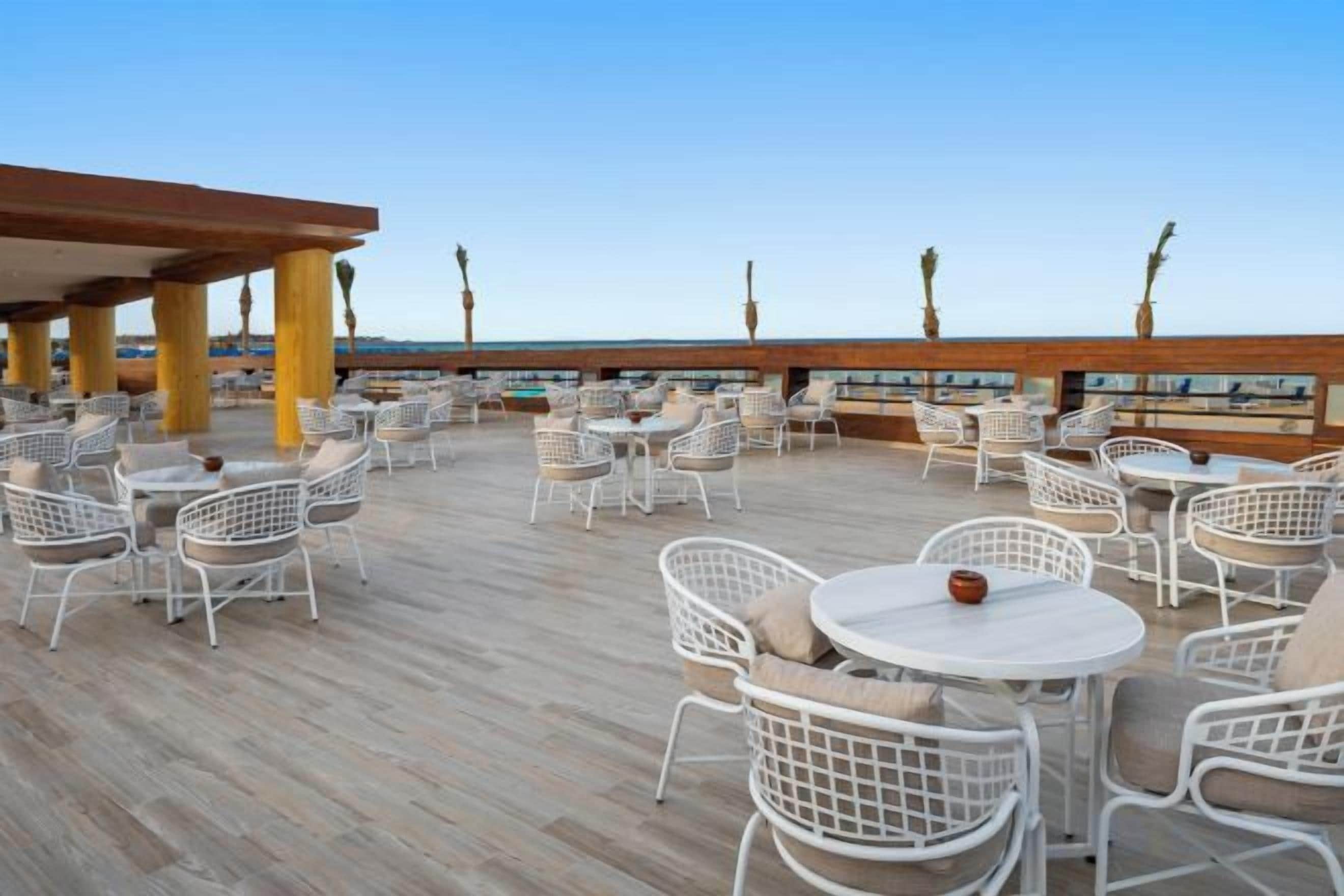 Een terras op het dak met buitenmeubels, een houten terras en uitzicht op zee.