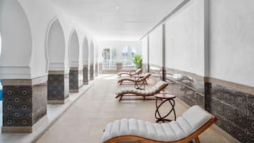 Un couloir agrémenté de fauteuils confortables, d’une plante et offrant une vue sur l’extérieur.