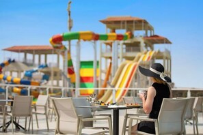 Un restaurante frente al mar con terraza y vista a un parque acuático.
