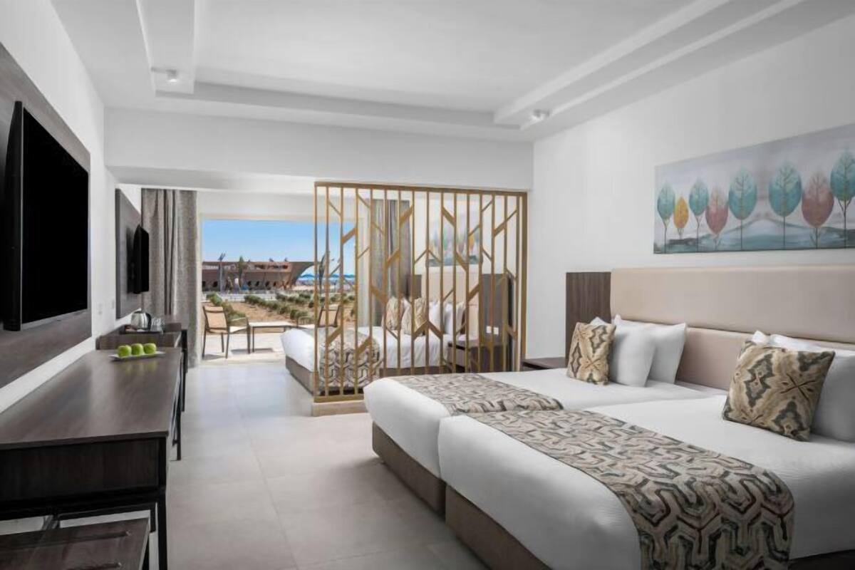 Ein Hotelzimmer mit Bett, Schreibtisch, Fernseher und Blick ins Freie.