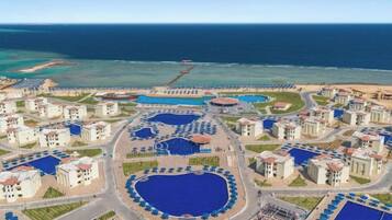 A resort with multiple swimming pools, beachfront villas, and a beach.