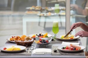 Ein Frühstückstisch mit verschiedenen Speisen, darunter Obst, Gebäck und einem grünen Getränk.