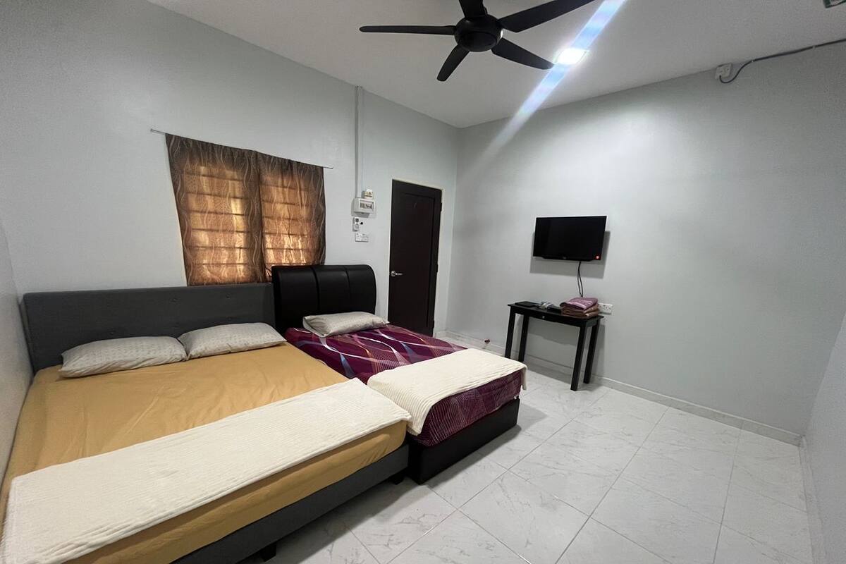 A bedroom with a bed, a ceiling fan, a TV, and a door.