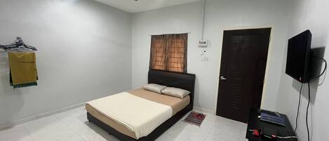 A bedroom with a bed, a ceiling fan, a TV, and a door.