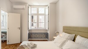 A bedroom with a bed, a window, a radiator, and a door. - Bairro Alto Garden by Homing (Lisbon)