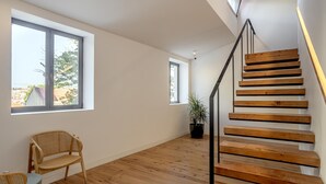 A spacious room with a wooden staircase, large windows, and a potted plant. - Bairro Alto Garden by Homing (Lisbon)