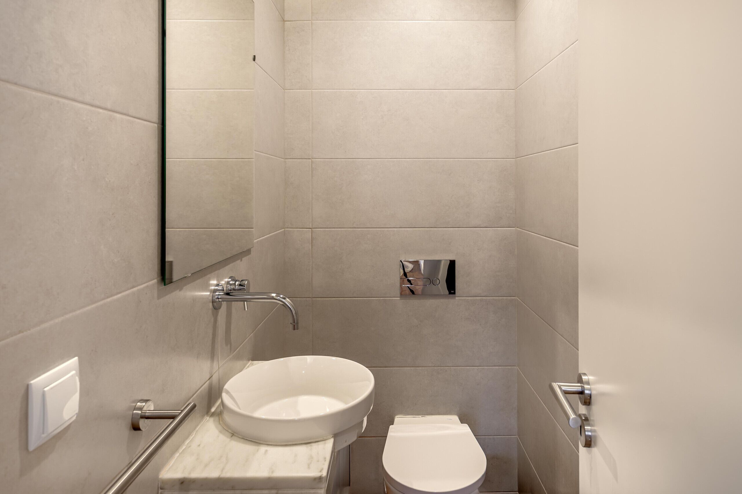 A modern bathroom with a white sink, toilet, and a mirror.