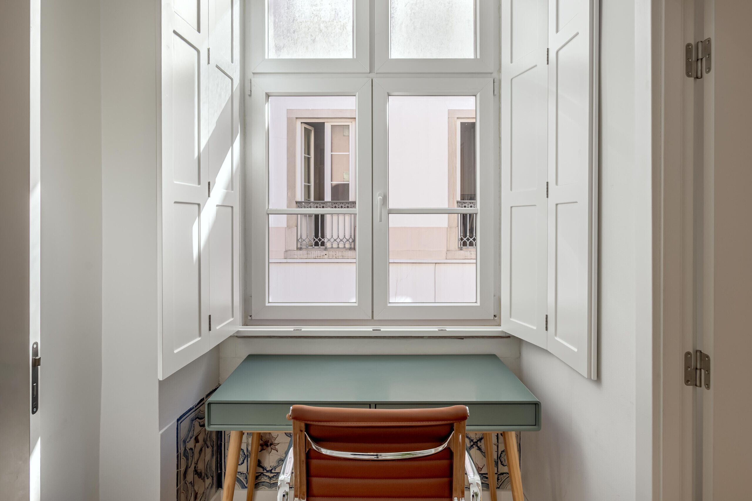 Een hoekappartement met een inbouw bureau en uitzicht door een raam.