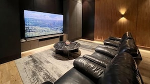 A modern living room with a large flat-screen TV, leather sofa, and a patterned rug. - Newly Studio Apt w/ Pool, Gym Netflix (South Jakarta)